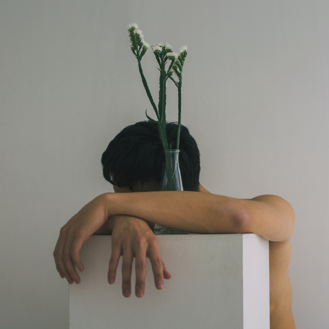 Man resting his head and holding a vase of flowers