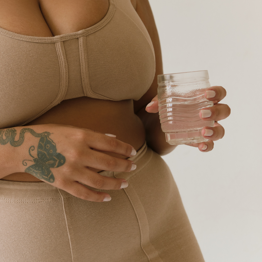Black woman in workout outfit holding a glass of water